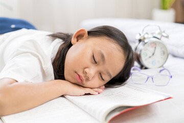 Asian child little girl sleep, tired from reading a book on the bed