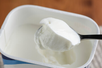 パック容器のプレーンヨーグルトをスプーンで掬って食べる