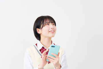 白背景でスマホを使いながら考える女子高生