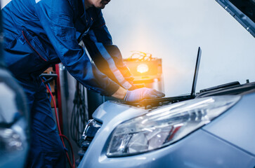 Close up hands of auto electrician using a computer laptop to diagnosing and checking up on car...