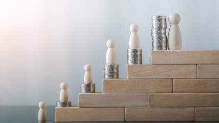 Wooden dolls and stacks of coins are placed on wooden blocks.
