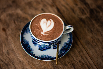 Hot chocolate with heart shape on the table brown wood.
