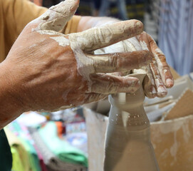 hand of the expert potter while shaping a clay pot using pressure on the material with fingers