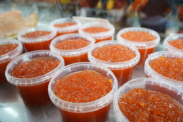 Almaty, Kazakhstan - 03.25.2022 : Sale of red caviar in plastic containers on the market.