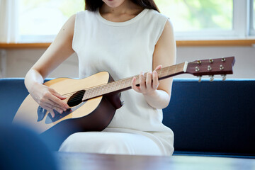 ソファーでギターを弾く日本人女性