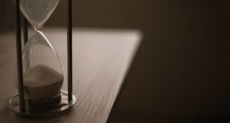 hourglass stand on wooden home office measuring time, try to meet deadline.