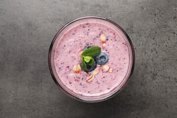 Glass of tasty blueberry smoothie with oatmeal on dark grey table, top view