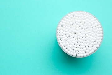 Many cotton buds in container on turquoise background, top view. Space for text