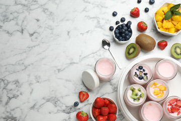 Modern yogurt maker with full jars and different fruits on white marble table, flat lay. Space for text
