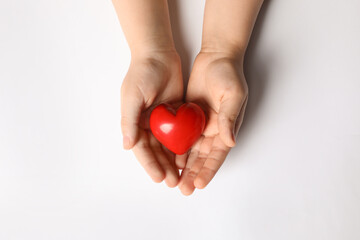Woman holding red heart in hands on white background, top view