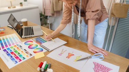 Fashion design concept, Asian female fashion designer sketching new clothes collection in atelier