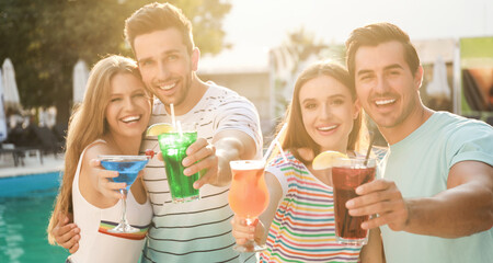 Happy young friends with fresh summer cocktails relaxing near swimming pool. Banner design