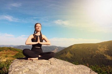 Fototapeta na wymiar Young woman practicing yoga in mountains on sunny morning