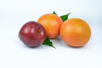 Two grapefruits and a burgundy apple on a white background.