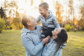 Happy family of mother and father carrying their boy child on shoulders. Smiling happy child....