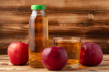 Apple juice in glass bottle with apples on table