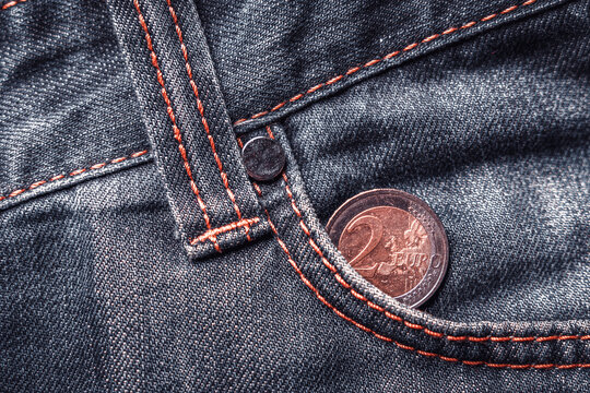 Two euro coin in the pocket of old shabby jeans