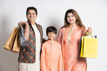 Happy young indian family holding shopping or gift bags. Asian parents with their child shopper...