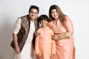 Happy young indian parents with their little son wearing ethnic festive outfit isolated over white...