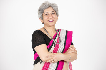 Happy senior indian woman wearing saree standing cross arms isolated over white background, Confident Asian elderly female looking at camera with folded hands.