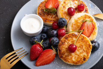 Close-up roasted cheesecakes on a plate with powdered sugar and berries angle view