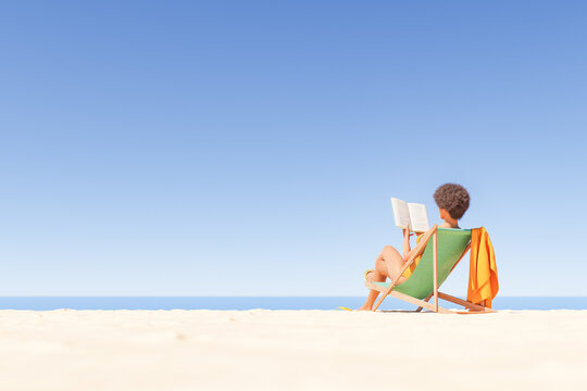 woman reading book on sandy seashore