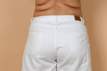 Closeup of female big waist with fat sides, love handles wearing white jeans. Body positive....