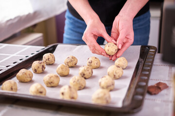 Woman holding ball of raw dough while making Chocolate chip cookies