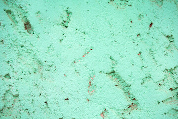 Fotografía frontal de una pared de cemento con textura arrugada y desgastada en ncolor verde agua...