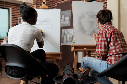 Diverse team working at art project drawing vase sketch on white canvas using illustration technique. Women students attending sketching lesson learning new artistic skill for personal growth