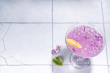 Obraz na płótnie Canvas Lilac drink. Alternative organic natural daikiri cocktail or mocktail, infused drink from lilac flowers. Lilac lemonade with ice in margarita cocktail glass