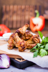 Spicy Homemade Buffalo wings with sauce, beer, tomatoes and herbs on a wooden board. Restaurant serving.