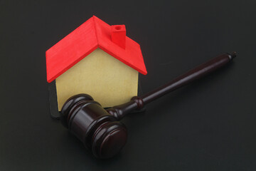 Tax, real estate business and auction concept. Judge gavel and house model on black background.	