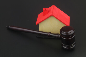 Real estate laws and auction concept. Wooden judge gavel and house model on black background.	