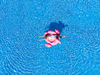 Woman on flamingo pool float in sea, drone aerial view. Enjoying summer vacations during quarantine. Summer holidays, relaxation.