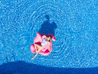 Summer holidays, relaxation. Woman on flamingo pool float in sea, drone aerial view. Enjoying summer vacations during quarantine.