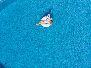 Beautiful woman on unicorn pool float in pool in the hotel. Summer holidays. Aerial top view from drone