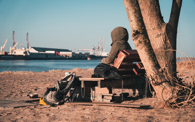 Young woman with warm clothes sitting at Harriersand beach at a riverbank during golden hour. Weser...