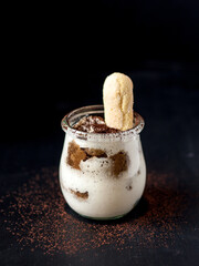 Delicious italian dessert tiramisu in a jars on a dark slate, stone or concrete background.