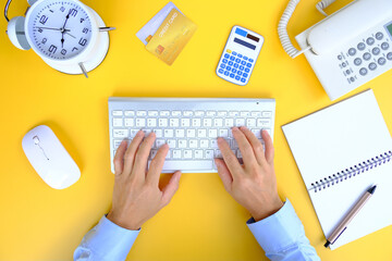 Man typing on his laptop keyboard on top of a white office desk table. Flat lay, top view with copy space.