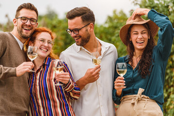 Happy friends having fun drinking wine at winery vineyard - Friendship concept with young people enjoying harvest time together