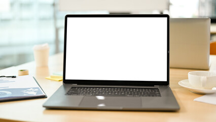 Fototapeta na wymiar Notebook laptop computer white screen mockup on meeting table. close-up image