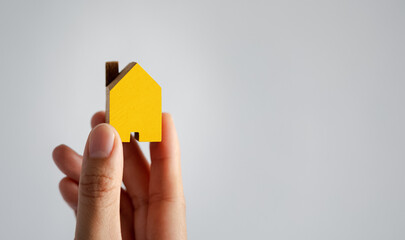 closeup woman hand holding yellow home model