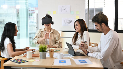 Fototapeta premium A group of Millennial technician having a meeting, testing their new virtual innovation on VR