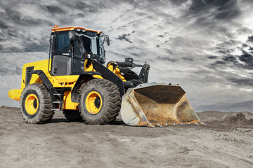 Bulldozer or loader moves the earth at the construction site against the sunset sky. Contrasting image of a modern loader or bulldozer. Construction heavy equipment for earthworks.