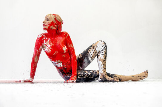 Young artistic sexy naked sitting woman in red, black and white hue color paint bodypainting, Creative, abstract body art, with colorful painting