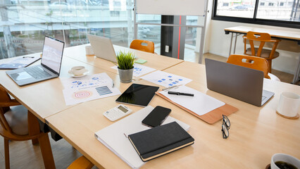 Messy office meeting table with notebook laptop, tablet and stuff