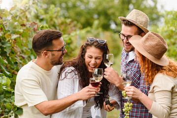 Happy friends having fun drinking wine at winery vineyard - Friendship concept with young people enjoying harvest time together