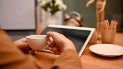 A female office worker or business entrepreneur sipping a hot coffee at office desk.