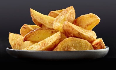 Kartoffel Wedges in einer Steingutschale vor schwarz